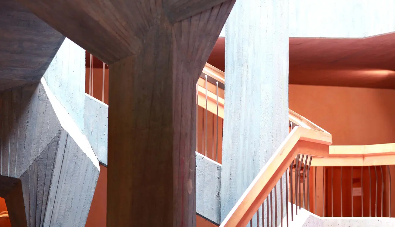 Treppenhaus der Schule mit Säulen aus Sichtbeton und Holzgeländern