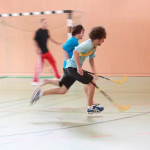 Jugendliche spielen in der Turnhalle Floorball