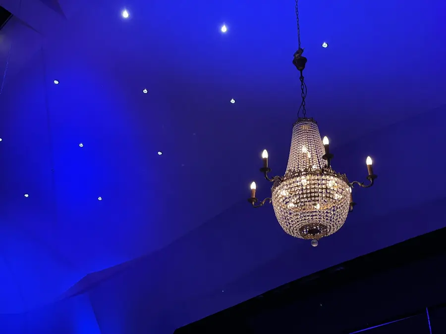 Kronleuchter an einer blau beleuchteten Decke