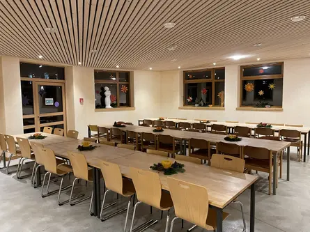 Der Speisesaal der Schulküche mit langen gedeckten Holztischen