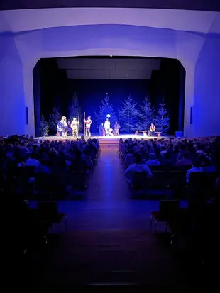 Aufführung des Christgeburtspiels auf der blau beleuchteten Bühne vor vollbesetztem Saal